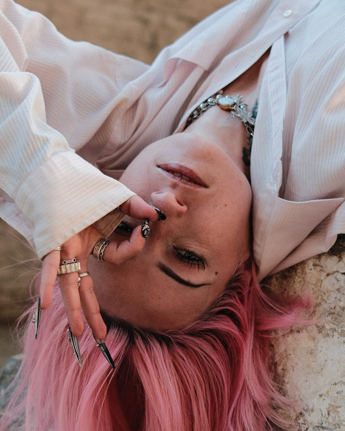 A portrait made upside down against a stone ledge, pink hair spilling toward the ground.